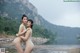 A couple of naked women standing next to each other near a river.