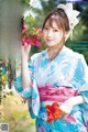 A woman in a blue and pink kimono holding a flower.