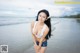 A woman in a white bikini standing on a beach.