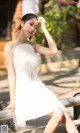 A woman in a white dress sitting on a bench.