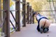 A woman in a school uniform crouching down on a bridge.