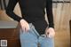 A woman in a black bodysuit is showing off her jeans.