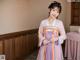 A woman in a purple and orange hanbok standing in a room.