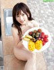 A naked woman holding a plate of fruit.