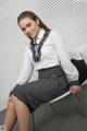 A woman sitting on a chair wearing a white shirt and black and white striped skirt.